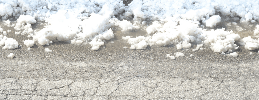 cracked asphalt partially covered in snow