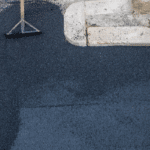 asphalt being laid with worker standing with shovel