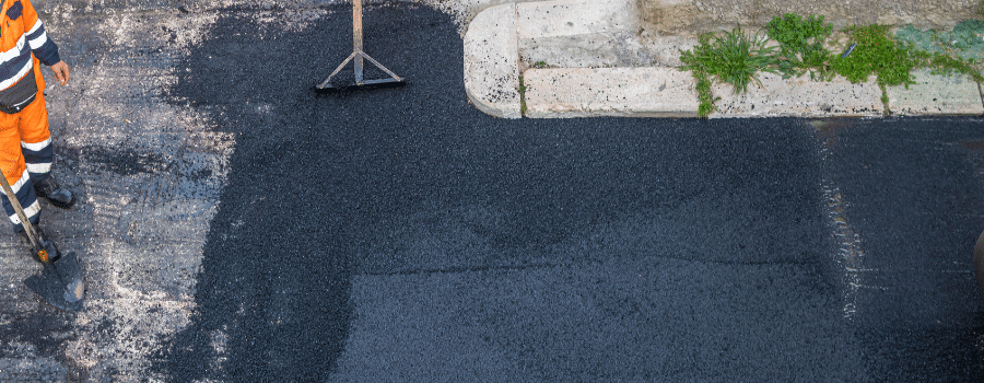 asphalt being laid with worker standing with shovel