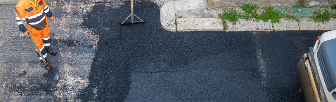 asphalt being laid with worker standing with shovel