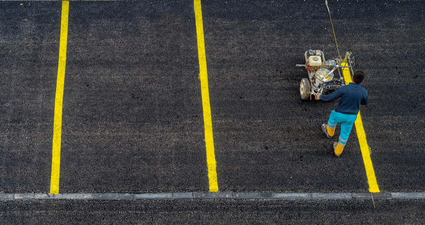 man using machine to paint parking lot lines