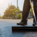 worker applying sealcoat on asphalt