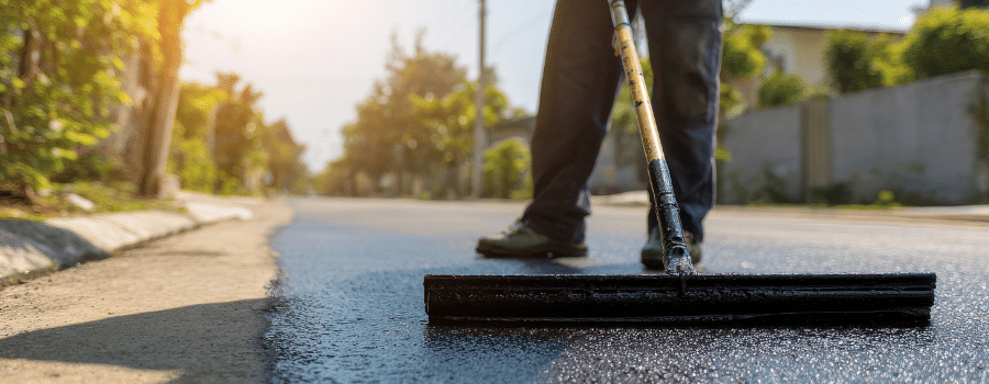 worker applying sealcoat on asphalt