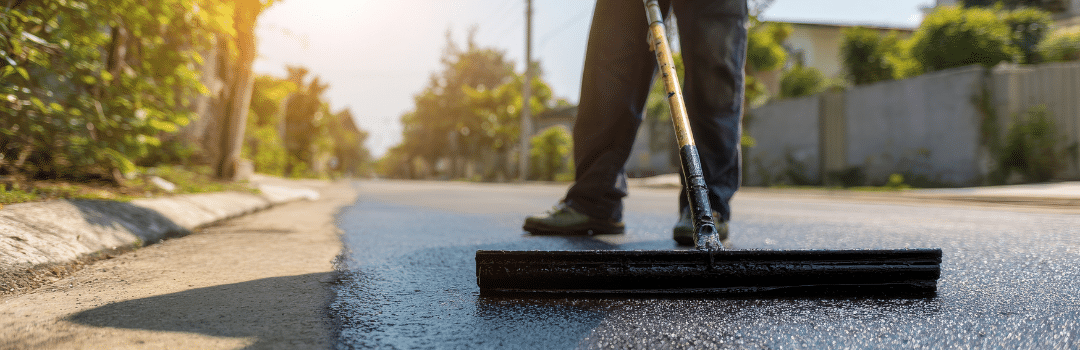 worker applying sealcoat on asphalt